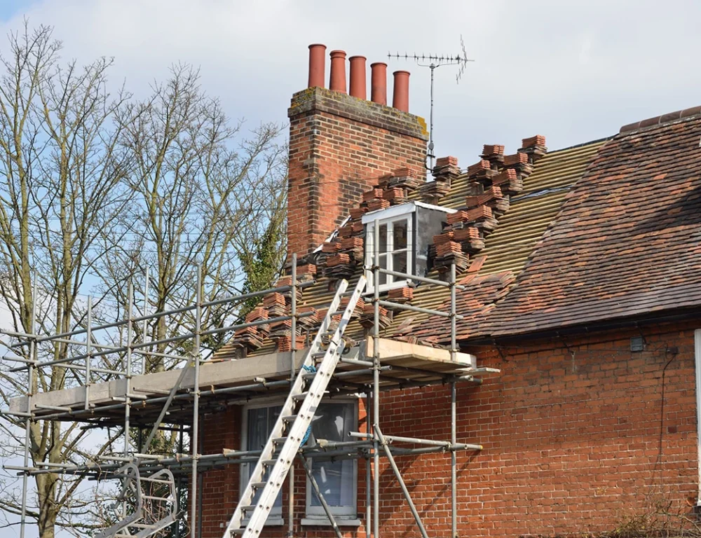 A roof being repaired with scaffolding, ladder and replacement bricks.